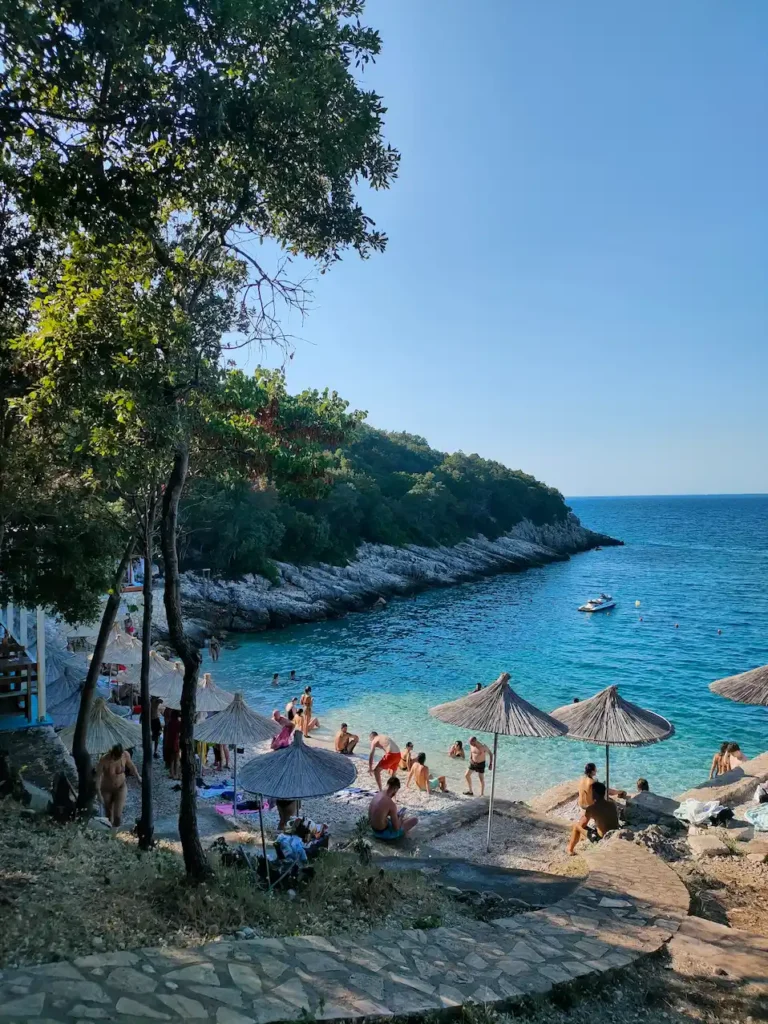 Beach on the Karaburun Peninsula near Vlore, Albania, with turquoise Ionian Sea waters and visitors relaxing