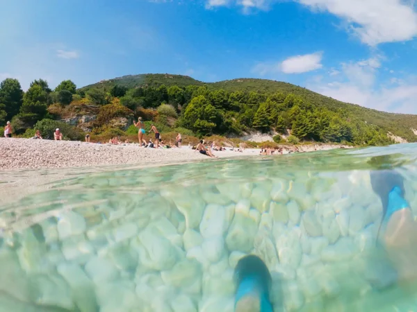 Crystal-clear Ionian Sea waters and pebble beach on Sazan Island near Vlore, Albania, during a boat tour stop along the Karaburun Peninsula