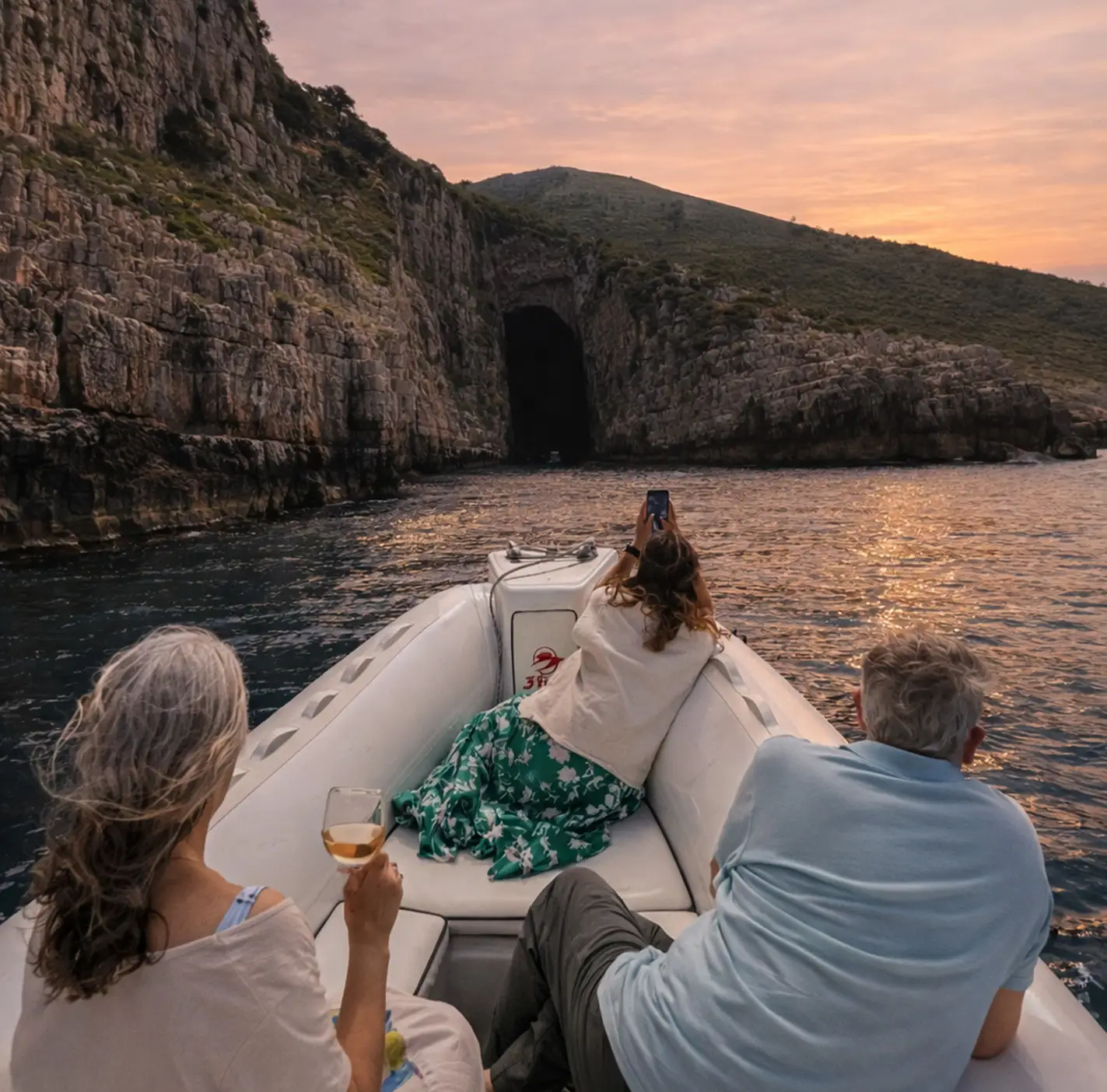 Sunset speedboat experience approaching Haxhi Ali Cave in Vlore with guests enjoying wine while sailing along the Karaburun coastline during golden hour.